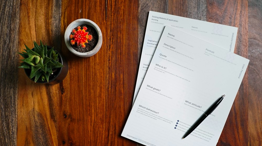 A wooden table with papers and a pen